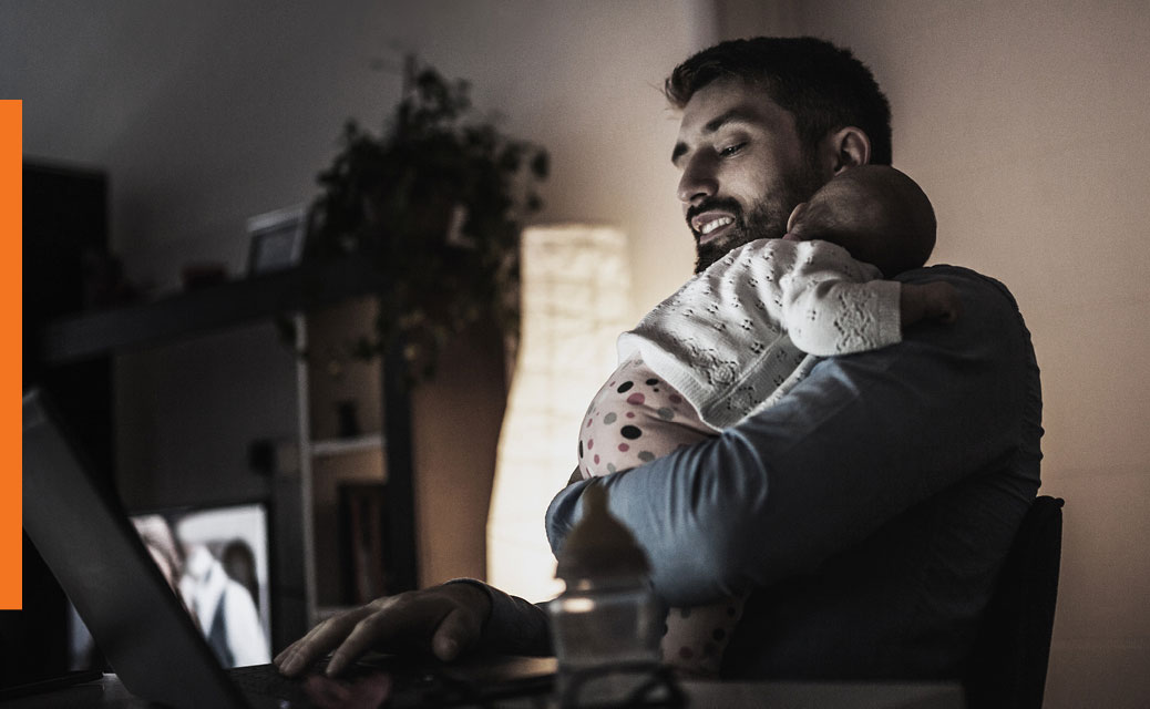 A man is looking at his smartphone while holding his baby